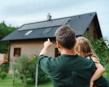 Mann mit Kind vor Solaranlage