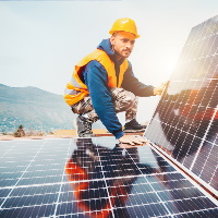 Junger Installateur auf einem Dach mit Photovoltaik-Modulen