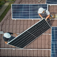Installateure auf einem Dach mit PV-Paneelen von der Vogelperspektive